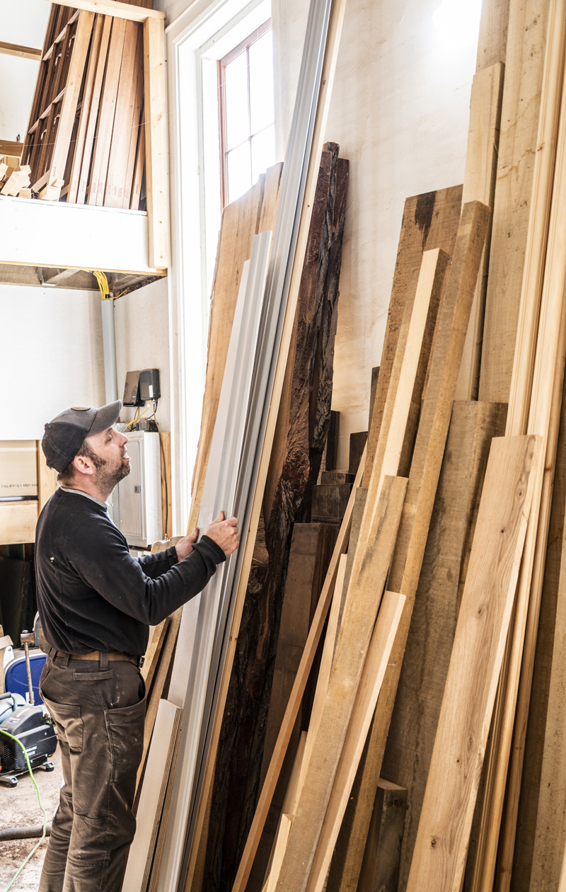 David Stetson selects a board at White Chapel Joinery in Edgecomb on April 3. The high-ceilinged space allows him to easily stand 16-foot-long boards on end while working. (Bisi Cameron Yee photo)