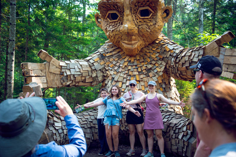 Visitors to Coastal Maine Botanical Gardens pose with one of the five trolls on the grounds. (Photo courtesy Coastal Maine Botanical Gardens)