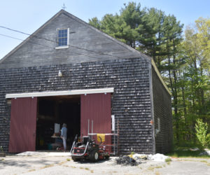 The old Keene barn at the intersection of Route 32 and Biscay Road in Bremen has housed a number of businesses throughout its 200-plus years. Today it houses Maine Coast Rope Rugs. Business owner Dara Kilpatrick is seen in the doorway weaving a rug from reused lobster float rope. (Elizabeth Walztoni photo)