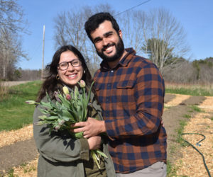 Laura Azevedo-Dominguez and Leo Azevedo, owners of Three Little Buds farm in Newcastle, stand with a fresh bouquet of tulips among their flower beds. The couple offers flowers and eggs at their home farm stand, along with bouquets at local retailers and custom orders. They hope to add a U-pick option this year. (Elizabeth Walztoni photo)