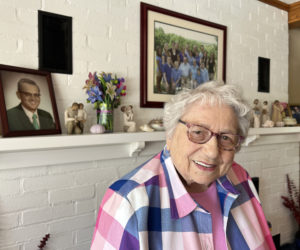 Lillian Dolloff at home, with a photograph of her husband Ronald Dolloff on the left, and another of her family on the wall behind her.