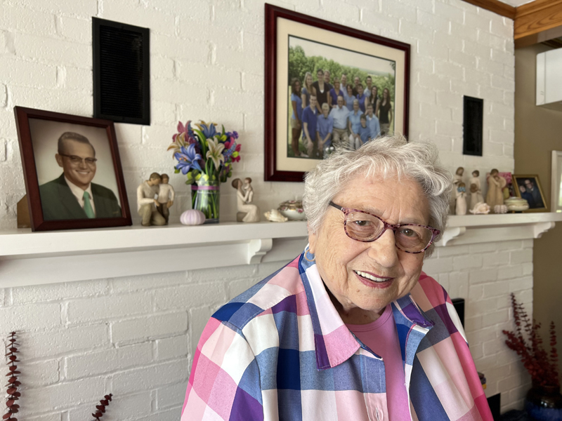 Lillian Dolloff at home, with a photograph of her husband Ronald Dolloff on the left, and another of her family on the wall behind her.