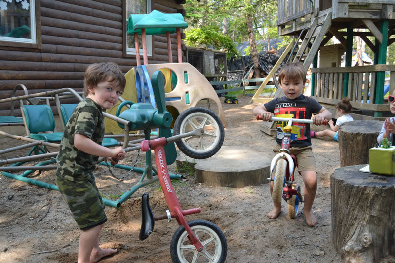 Four-year-olds Casen Weatherbee (left) and Otto MacCready race around the front yard of Harbor Day Care in Bristol on bikes. Laurie Mahan, founder of Harbor Day Care, puts an emphasis on playing outside. (Johnathan Riley photo)