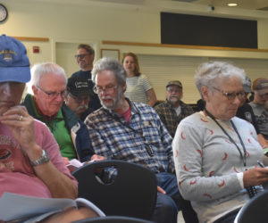 Newcastle voters review warrant articles before the annual town meeting begins on Tuesday, June 20. More than 50 voters attended the meeting in the Lincoln Academy dining commons. (Elizabeth Walztoni photo)