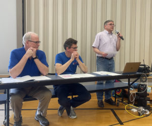 Somerville Select Board Chair Chris Johnson addresses the annual town meeting held in Somerville Elementary School gymnasium on Saturday, June 24. From left: select board members Donald Whitmer-Kean, Don Chase, and Johnson. (Sherwood Olin photo)