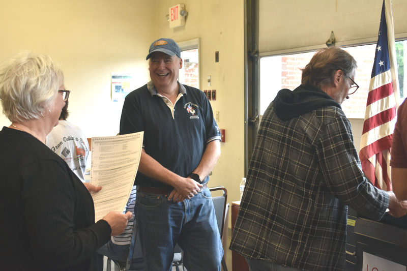Mark Stults laughs with voters as he mans the ballot box in Waldoboro on Tuesday, June 13. (Elizabeth Walztoni photo)