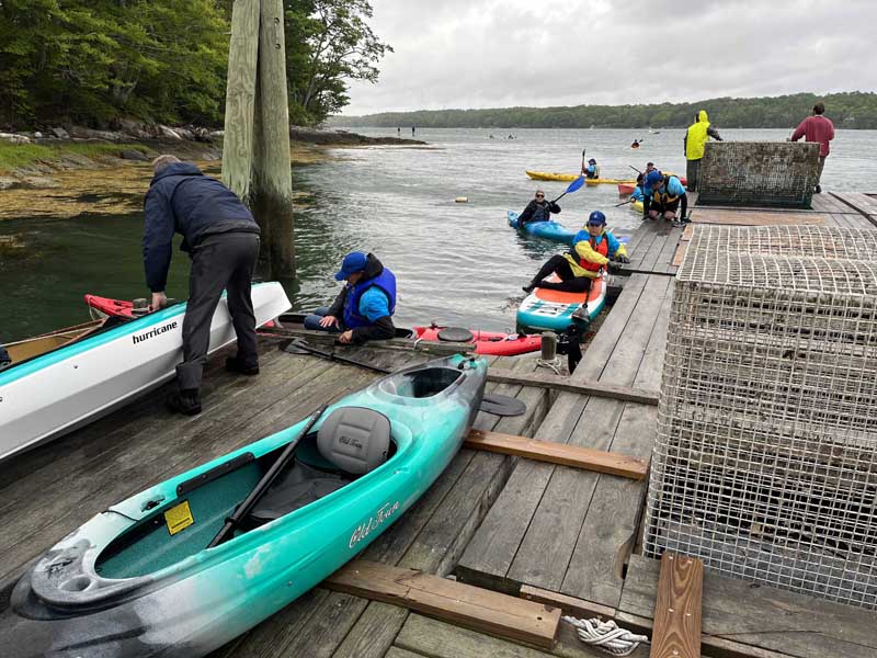 Staff from Glidden Point Oyster Farms and Midcoast Kayaks assist wet, hardy paddlers as they arrive at the Paddle for a Purpose celebration at Glidden Point Oyster Farms in Edgecomb on Saturday, June 3. (Mic LeBel photo)