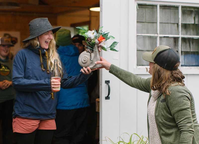 Holly Zeller (left) wins the Smelled the Roses Award for slowest paddler to arrive on shore and gets a snail and rose bouquet from Hearty Roots Executive Director Haley Bezon. (Mic LeBel photo)