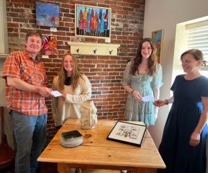 Damariscotta River Grill Owners, Tim Beal and Tamara Dica present Art at the Grill scholarships to Maddy Scott and Ella Appell, standing in front of their artwork. Missing from the photo is Claire Colburn, whose pottery is on the front of the table. (Photo courtesy Kim Traina)