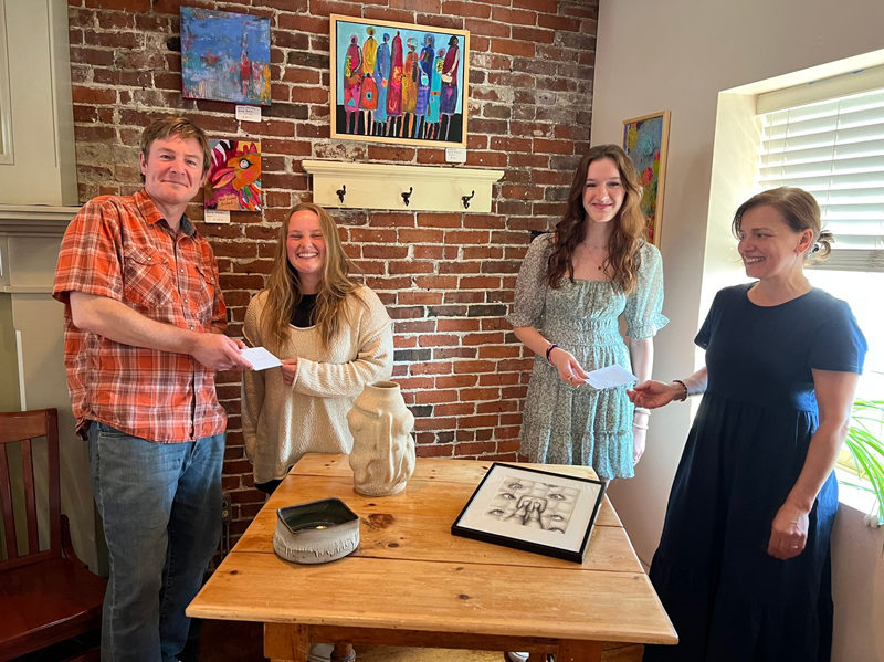 Damariscotta River Grill Owners, Tim Beal and Tamara Dica present Art at the Grill scholarships to Maddy Scott and Ella Appell, standing in front of their artwork. Missing from the photo is Claire Colburn, whose pottery is on the front of the table. (Photo courtesy Kim Traina)