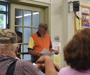 Jon Young, senior warden for St. Philip's Episcopal Church in Wiscasset, reviews documents before the town's select board meeting on Tuesday, July 18. Residents filled the municipal meeting room and the entryway seen behind Young to comment on a business license proposal from Amistad Inc. for a peer recovery and community center it has proposed in partnership with the church. (Elizabeth Walztoni photo)