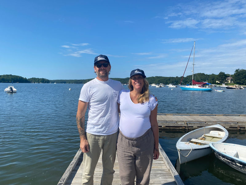 Meredith Spratt and Logan Livingston stand in front of the Damariscotta River. The couple is offering river tours and day charters with their business, Sandpiper Maine Excursions, through which guests are able to learn about the river, enjoy the views, and go swimming. (Frida Hennig photo)