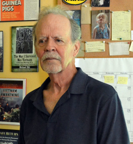 Vietnam War veteran and author Michael Uhl stands in the study of his Walpole home against a backdrop of some of his previous books. Writing on topics from travel to war, Uhl published his most recent book this past May. (Johnathan Riley photo)