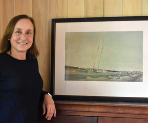 Jamie Hanna stands with "Low Tide at Damariscotta," a painting from about 1970 by her father, David Hanna, of a schooner that sank in Misery Gulch. She has spent the past five years finding and cataloging his works with the hope of staging the first exhibiton of his work since his early death in 1981. (Elizabeth Walztoni photo)