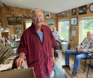 Bruce Soule in his barber shop in Waldoboro, his hand on the old cash register he still uses because the new cash register that his wife gave him made him feel that a simple dollar bill was a thousand dollar bill, and that feeling was too uncomfortable.