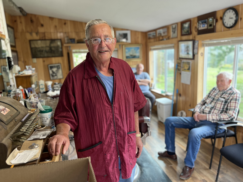 Bruce Soule in his barber shop in Waldoboro, his hand on the old cash register he still uses because the new cash register that his wife gave him made him feel that a simple dollar bill was a thousand dollar bill, and that feeling was too uncomfortable.