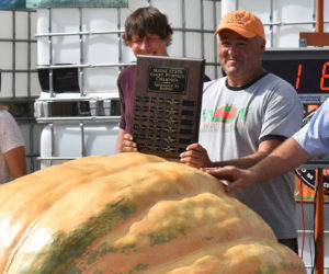 Scott St. Laurent, of Lyman, holds the Maine state giant pumpkin champion plaque on Sunday, Oct. 1 after taking first with a 1,958-pound pumpkin in the weigh-off at Louis Doe Home Center. St. Laurent has entered the competition for the past six years and took home his first win Sunday. "I'm with the big boys now," he said with a smile. (Elizabeth Walztoni photo)