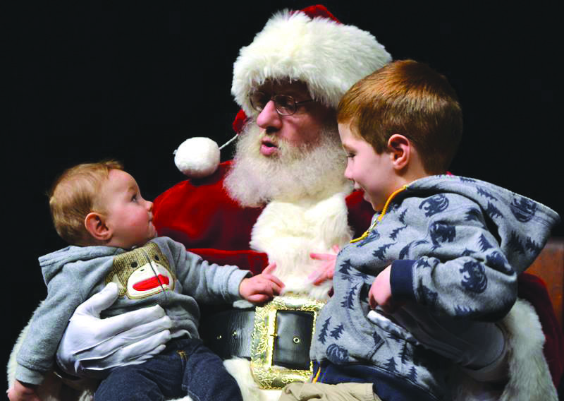 Santa Claus greets two young visitors during Villages of Light. The committee is seeking additional volunteers for the seventh annual event. (Courtesy photo)