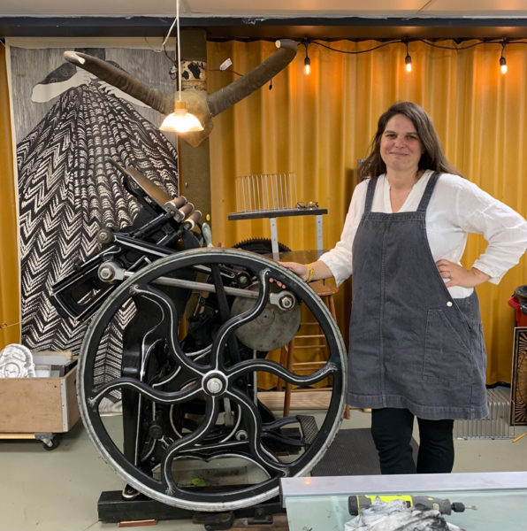 Lisa Pixley stands in front of her 1890's Chandler & Price old style Platen Press at Grand Army Arts Print Studio in Whitefield. (Photo courtesy Mary Dunn)