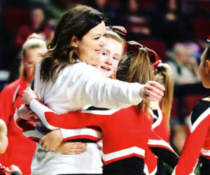 Coach Brie McCarthy gets a hug from her team after they came off the floor at the Maine state cheer championships in March. (Courtesy photo)