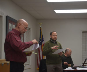 Newcastle Town Manager Kevin Sutherland (right) explains a warrant article to voters while moderator David Levesque reads materials at a special town meeting on Monday, Dec. 11. Voters considered repeal and replacement of the town's bidding and purchasing policy, along with amendments to two sections of the core zoning code. An amendment that would have brought more multi-unit housing proposals before the planning board failed with a close vote following lengthy discussion with the public about the parts of the code. (Elizabeth Walztoni photo)