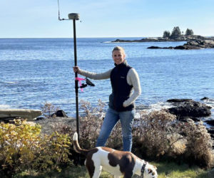 Anne Howell and Scout, of SurveyScapes, on site with survey equipment in New Harbor. Howell and business partner Stephanie Mazerolle described their work as putting together a mathematical puzzle, researching the deed histories of properties and then visiting the site to look for boundary clues. (Courtesy photo)