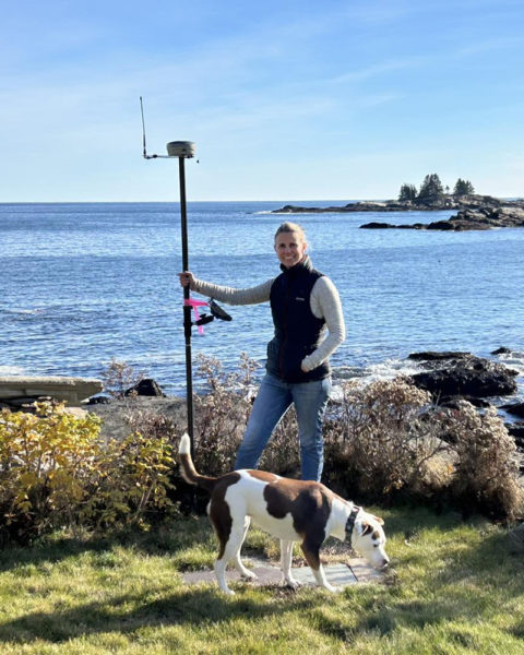 Anne Howell and Scout, of SurveyScapes, on site with survey equipment in New Harbor. Howell and business partner Stephanie Mazerolle described their work as putting together a mathematical puzzle, researching the deed histories of properties and then visiting the site to look for boundary clues. (Courtesy photo)