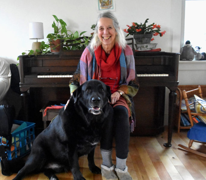 Kaity Newell sits in her music room at home in Damariscotta with her dog, Bruce. A local music teacher in the area for 40 years, she has started or been a founding member of long-lived music institutions Maine Country Dance Orchestra, Oyster Creek Fiddlers, Maine Fiddle Camp, Seacoast Community Orchestra, local contra dances, and the strings program at Great Salt Bay Community School. (Elizabeth Walztoni photo)