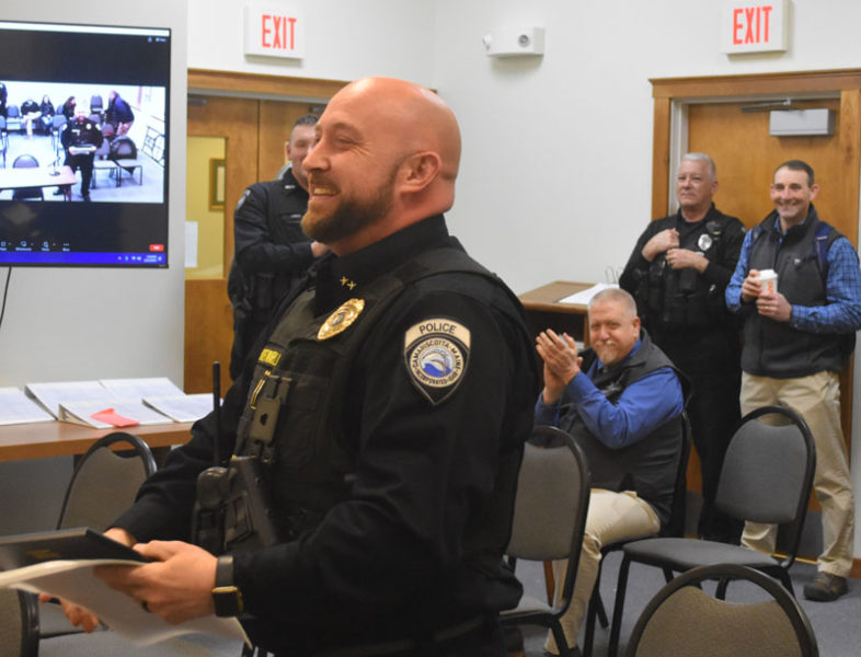 Damariscotta Police Chief Jason Warlick (left) receives a plaque recognizing the department's accreditation through the Maine Law Enforcement Accreditation Program while fellow law enforcement officials applaud. After months in the works, the department received the recognition at the select board's meeting Tuesday, Feb. 22. (Elizabeth Walztoni photo)