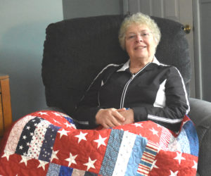 Pat Johnston at home in Nobleboro with one of her Quilts of Appreciation, which she has spent years making for local veterans. Johnston said seeing the reactions of recipients at the presentation events she hosts is her payment for the work. (Elizabeth Walztoni photo)