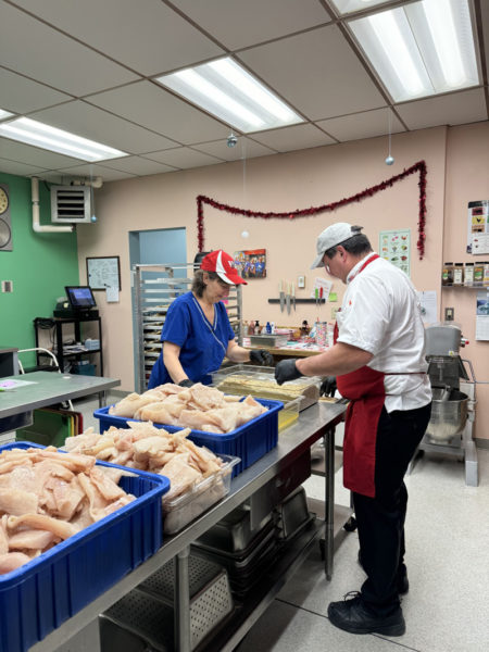Mike Flynn and Vicki Dill prepare haddock from the Fishermen Feeding Mainers program for Whitefield Elementary School students. (Photo courtesy Michaela Stone)
