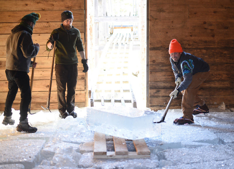 Volunteers wrangle an incoming block of ice inside the Thompson Ice House during the 2018 ice harvest. (Jessica Picard photo, LCN file)