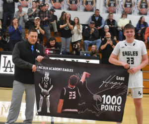 Head coach Ryan Ball and Gabe Hagar hold up a banner recognizing the senior's 1,000th point for the Eagles. (Mic LeBel photo)