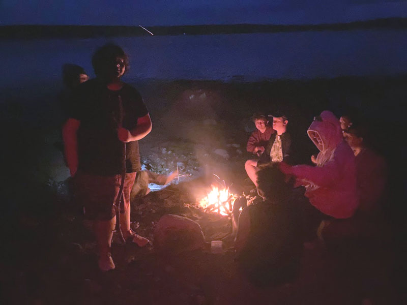 Teens cook and chat by the fire during an overnight adventure. (Photo courtesy Hearty Roots)