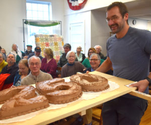 Forrest Carver carries Edgecomb's ceremonial 250th birthday cake to be cut at a party in the town hall on Sunday, March 17. Celebratory events will continue throughout the year, including a road race, an ice cream social, local business tours, and a potluck supper with local storytelling. (Elizabeth Walztoni photo)