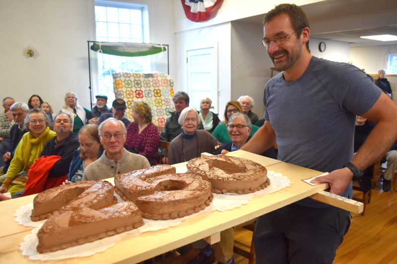 Forrest Carver carries Edgecomb's ceremonial 250th birthday cake to be cut at a party in the town hall on Sunday, March 17. Celebratory events will continue throughout the year, including a road race, an ice cream social, local business tours, and a potluck supper with local storytelling. (Elizabeth Walztoni photo)