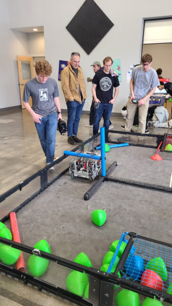 Lincoln Academy Robotics Team 8030A practices in the arena at the state championships while Head of School Jeff Burroughs looks on. From left: Senior Mica Houghton, Jeff Burroughs, junior Joseph Levesque, and senior Connor Parson. (Photo courtesy Lincoln Academy)