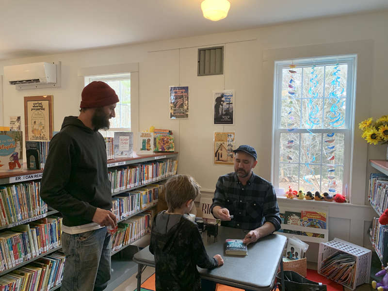 Peter Brown, author and illustrator of several award-winning and delightful childrenÂ’s books, signs a special copy of his book, "The Wild Robot," for one of Whitefield LibraryÂ’s young readers. (Photo courtesy Cheryle Joslyn)