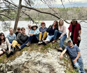 Hearty Roots staff and board members sit on a rock on the newly acquired land in Bremen that will serve at the organizations headquarters on Wednesday, May 15. From left: Hearty Roots board member Ashley Baldwin, Treasurer Heather Abello, Therapeutic Adventure Mentor Lauren Cucci, Business Manager Katherine Kirchoff, board President Ali Stevenson, board Secretary Lisa Katz, Hearty Roots Deputy Director Jess Donohoe, Hearty Roots Director Haley Bezon, supporter Eleanor Kinney, Hearty Roots Program Manager Josh Leatham, and supporter Steve Page. (courtesy photo)