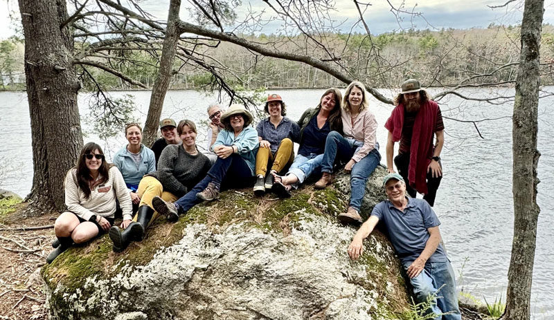 Hearty Roots staff and board members sit on a rock on the newly acquired land in Bremen that will serve at the organizations headquarters on Wednesday, May 15. From left: Hearty Roots board member Ashley Baldwin, Treasurer Heather Abello, Therapeutic Adventure Mentor Lauren Cucci, Business Manager Katherine Kirchoff, board President Ali Stevenson, board Secretary Lisa Katz, Hearty Roots Deputy Director Jess Donohoe, Hearty Roots Director Haley Bezon, supporter Eleanor Kinney, Hearty Roots Program Manager Josh Leatham, and supporter Steve Page. (courtesy photo)