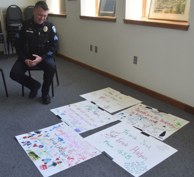 Damariscotta Police Sgt. Erick Halpin reads well-wishes from students at Great Salt Bay Community School during a celebration at the town office on Tuesday, May 7. The students created the signs for Halpin's last day with the department. (Maia Zewert photo)