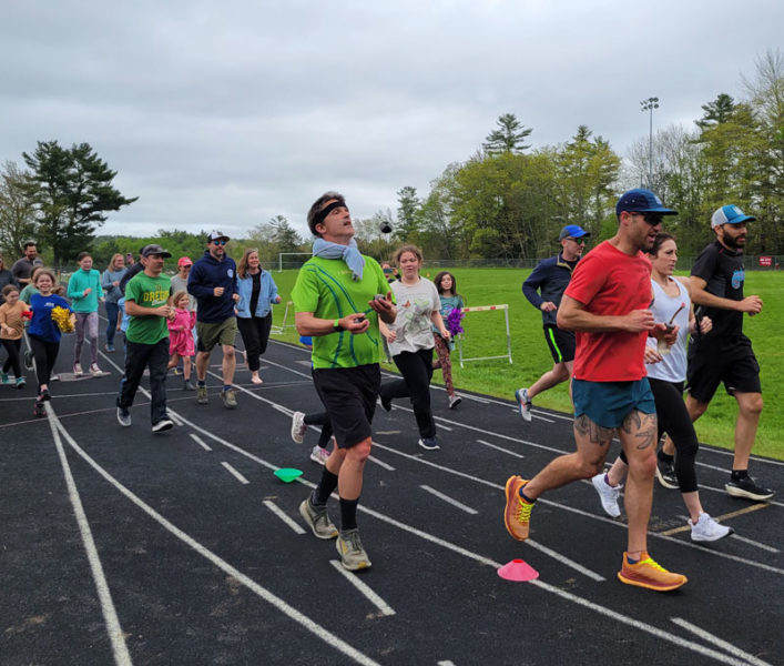 Friends, family, and students join South Bristol School teacher and endurance runner Jason Bigonia on his final lap of 191 while joggling around the track in Wiscasset. (Courtesy photo)