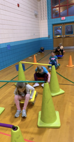 Kindergartners duck while maneuvering their scooters through an obstacle course during physical education class at Nobleboro Central School. (Photo courtesy Nobleboro Central School)