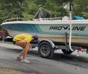 With permission, a courtesy boat inspector looks over a boat at the Pemaquid Pond boat landing in Nobleboro. (Photo courtesy Coastal Rivers Conservation Trust)