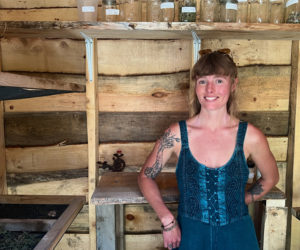 Homesteader and herbalist Deirdre Haren stands in her drying shack in North Waldoboro surrounded by trays of plant leaves that she uses for formulating her teas.