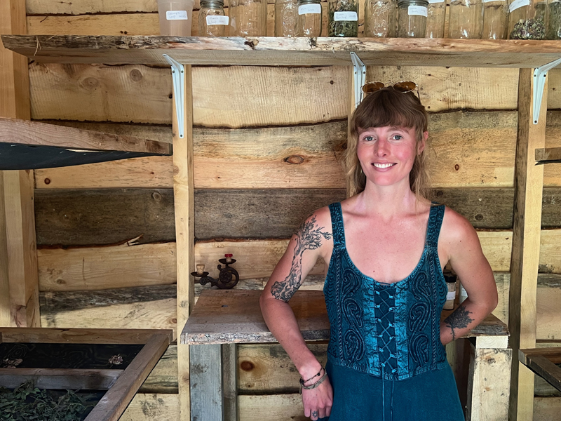 Homesteader and herbalist Deirdre Haren stands in her drying shack in North Waldoboro surrounded by trays of plant leaves that she uses for formulating her teas.