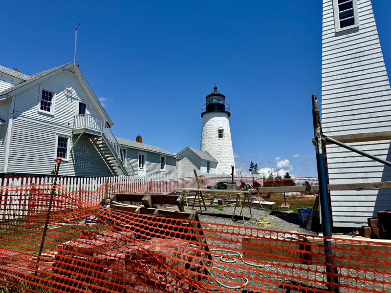 Pemaquid Point Lighthouse overlooks the bell house construction site on Thursday, June 27. In addition to repairs to the bell house, the eastern wall of the building attached to the lighthouse had its siding replaced and the white picket fence was recemented after sustaining damage in severe twin storms in January. (Johnathan Riley photo)