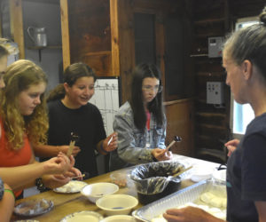 From left: Sixth and seventh grade RSU 40 students Elaine Ernest, Bella Billings, Madelyn Lermond, and Aurelia Kozubal make s'mores using math skills with guidance from Medomak Camp co-Director DeAnn Vigue. Making s'mores was the camp's "special activity" of the day on Monday, July 29, with each child participating over the course of the day. (Molly Rains photo)