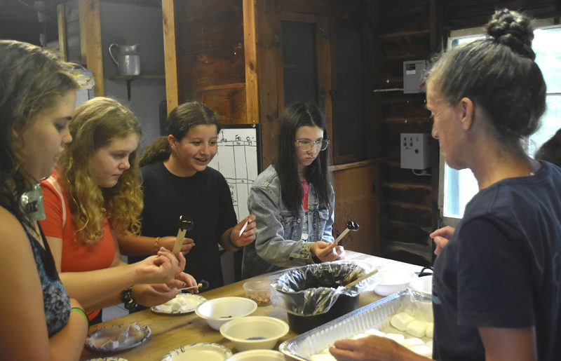 From left: Sixth and seventh grade RSU 40 students Elaine Ernest, Bella Billings, Madelyn Lermond, and Aurelia Kozubal make s'mores using math skills with guidance from Medomak Camp co-Director DeAnn Vigue. Making s'mores was the camp's "special activity" of the day on Monday, July 29, with each child participating over the course of the day. (Molly Rains photo)