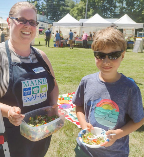 Healthy Lincoln County SNAP educator Samantha Mehlhorn (left) and local student enjoy a summer salad at the Damariscotta Farmers Market. (Photo courtesy Healthy Lincoln County)